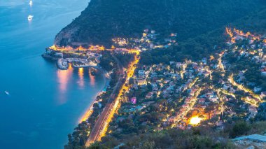Günbegün Akdeniz kıyı şeridini teknelerle gösteren geçiş zamanı. Günbatımından sonra Fransız Rivierası 'ndaki Eze köyünün tepesinden ortaçağ evleri.