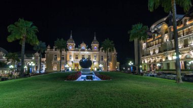 Monte Carlo 'da Grand Casino' yla birlikte Monaco 'da gece hiperhızlandırılmış zaman dilimi. Çevrede tarihi aydınlık binalar var. Tepedeki saat. Avuçlar yana..