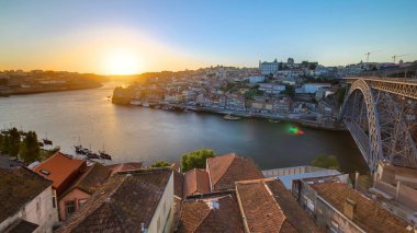 Panorama of old city Porto at river Duoro, with Port transporting boats at sunset timelapse with the Dom Luiz bridge, Oporto, Portugal