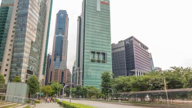 Skyline of Singapore city. Downtown skyscrapers office buildings of modern megalopolis timelapse hyperlapse. Traffic on a road. Reflections in glass surface and clouds on the sky.