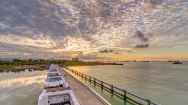 Marina Barrage panoramik zaman diliminde güzel bir gün doğumu. Turuncu gökyüzü ve güneş ışınlı bulutlar. Singapur 'un 15. su deposu ve şehrin göbeğindeki ilk su deposudur..