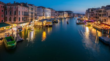 Grand Canal in Venice, Italy day to night transition timelapse. Aerial view on gondolas and city lights from Rialto Bridge. Beautiful and romantic Italian city on water.