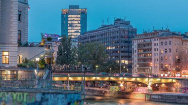 Viyana 'da Tuna kanalı ile Viyana şehir manzarası Viyana' da günden geceye geçiş zamanı. Avusturya. Yeşil ağaçlı binalar ve trafiği olan köprüler