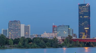 Günbegün modern binalarla dolu güzel şehir manzarası geçiş zamanı, Avusturya 'nın en uzun gökdeleni, gün batımından sonra Viyana' nın Donau bölgesindeki mavi Tuna nehrine yansıdı..
