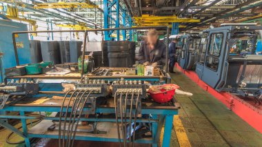 Konveyör montajı, traktörün gövdesini büyük endüstriyel fabrika zaman diliminde sahneleyecek. Kabin montajı, kurulum parçaları özel bir masada.