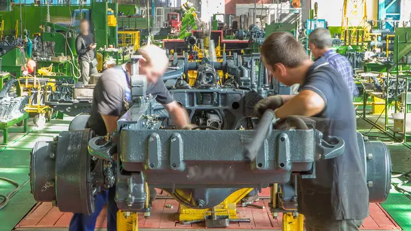 Konveyör montajı, traktörün gövdesini büyük endüstriyel fabrika zaman diliminde sahneleyecek. Çerçeve montajı, Chassis kurulumu ve diğer bölümler etrafındaki işçiler.