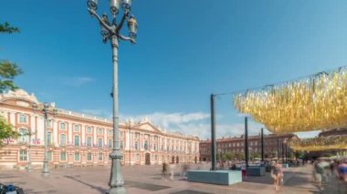 Capitole de Toulouse zaman çizelgesini gösteren panorama, Fransa 'nın Toulouse şehrinin tarihi belediye binasını ve belediye merkezini gösteriyor. Capitole Meydanı' nda mavi bulutlu gökyüzü altında birçok restoran bulunuyor.