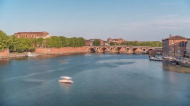 Toulouse, Fransa 'da Port de la Daurade ile Garonne Nehri ve Pont Neuf zamanapse. Bu Rönesans kemer köprüsü bulutlu mavi gökyüzünün altındaki suya yansıyor. Yeşil ağaçlı rıhtım