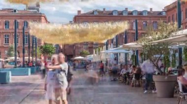 Fransa 'nın Toulouse şehrinde Capitole Meydanı' nda. İkonik kırmızı tuğlalı tarihi ön cephelerde açık hava kafeleri, beyaz şemsiyeler ve süslemeli ışıklandırmalar var. Canlı bir yaya istikameti.