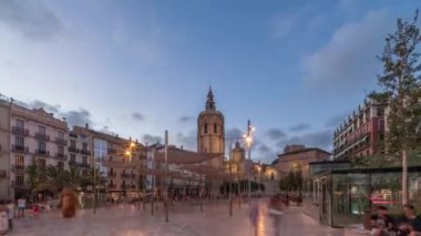 İspanya, Valencia 'daki Plaza de la Reina' da panoramik günden geceye geçiş süreleri aşırı hızlanıyor. Tarihi bir kilise kulesi, hareketli kafeleri ve akşam gökyüzünün altında merkezi bir çeşmesi olan canlı bir meydan..
