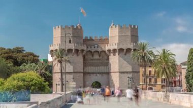 Serrans Kuleleri Torres de Serranos zaman atlaması. Valencia, İspanya 'da. Şehrin antik duvarlarından gelen büyük bir ortaçağ kapısı. Mavi gökyüzü altındaki hareketli sokak manzaraları bu tarihi yeri çerçeveler.