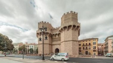 Serrans Kuleleri Torres de Serranos zaman atlaması. Valencia, İspanya 'da. Şehrin antik duvarlarından gelen büyük bir ortaçağ kapısı. Bulutlu bir gökyüzü altında hareketli bir sokak manzarası bu tarihi yeri çerçeveler.