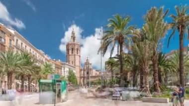 Valencia, İspanya 'da Plaza de la Reina' nın panoramik zaman atlaması. Tarihi bir kilise kulesi, hareketli kafeler ve sıcak Akdeniz semaları altında palmiyeleri olan merkezi bir çeşme..