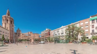 Panorama, İspanya, Valencia 'daki Plaza de la Reina' nın zaman çizelgesini gösteriyor. Tarihi bir kilise kulesi, hareketli kafeler ve sıcak Akdeniz mavi gökyüzünün altında merkezi bir çeşmesi olan canlı bir meydan..