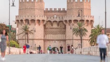 Serrans Kuleleri Torres de Serranos zamanapse Valencia, İspanya 'da. Şehrin antik duvarlarından gelen büyük bir ortaçağ kapısı. İnsanlar gün batımından önce tarihi bir dönüm noktasında köprüde yürüyorlar.