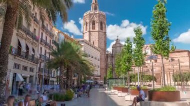 Valencia, İspanya 'daki Plaza de la Reina' nın panoramik zaman çizelgesi. Tarihi bir kilise kulesi, hareketli kafeler ve sıcak Akdeniz bulutlu gökyüzünün altında merkezi bir çeşme..