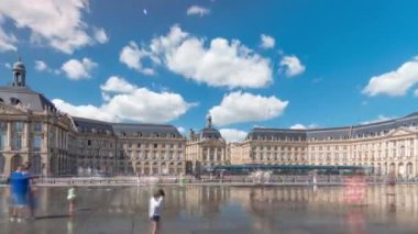 Place de la Bourse ve Miroir deau hiperlapse Bordeaux, Fransa 'da, tarihi mimariyi yansıtıyor. Turistler şehir simgesi ve çeşmenin tadını çıkarıyorlar. Trafik ve tramvay zamanı geçiyor..