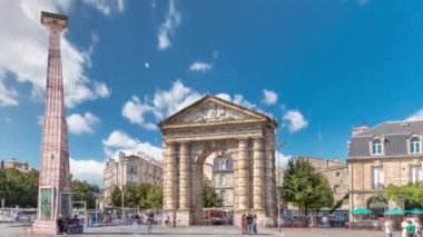 Fransa, Bordeaux 'da Place de la Victoire' da Porte dAquitaine kemeri ve dikilitaş. Tramvay hatları, kafeler ve mavi bulutlu gökyüzünün altında çevreleyen canlı Bordeaux 'nun tarihi simgesi.