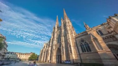 Saint-Andre de Bordeaux Katedrali, mavi bulutlu gökyüzünün altında ikiz kuleleri olan hızlandırılmış zaman atlaması. Meydanda yürüyen insanlar gün batımından önce sakin bir şehir atmosferi yaratıyorlar. Bordeaux, Fransa