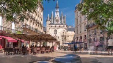 Fransa 'nın Bordeaux şehrinde ortaçağ mimarisi ve kuleleriyle birlikte tarihi Porte Cailhau zaman dilimi. Şehir manzaraları yeşil ağaçların altındaki restoranlar ve teraslarla birlikte geçidi ve canlı çevreyi gösteriyor.