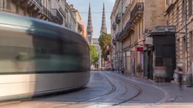 Vital Carles caddesinden Bordeaux Katedrali Katedrali Aziz Andre 'nin Timelapse' ında tarihi şehirde hareket eden bir tramvay yer alıyor. İnsanlar tramvay durağında bekliyor. Bordeauxların mirasının bir sembolü. Fransa