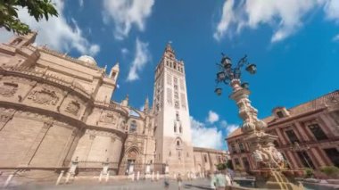 Virgen de los Reyes Meydanı, Seville Katedrali ve Giralda Kulesi zaman atlamalı Seville, İspanya 'da. Dünyanın en büyük gotik katedrali, mavi bulutlu gökyüzünün altındaki UNESCO miras alanı.