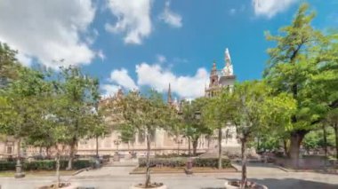 Plaza del Triunfo zaman atlaması ve Sevilla Katedrali 'nin kusursuz gebelik anıtı. Yeşil ağaçlar, tarihi mimari, bulutlu mavi gökyüzü. Endülüs, İspanya 'da manzara