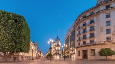 Avenida de la Constitucion, Seville, İspanya 'da günden geceye zaman dilimi. Modern sokak lambaları, yayalar ve kentsel atmosferi olan tarihi mimari. Iconic Adriatica binası gün batımından sonra parlıyor.