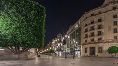 Avenida de la Constitucion gece vakti Seville, İspanya 'da aşırı hız. Iconic Adriatica binası akşam parlıyor. Modern sokak lambaları, yayalar ve şehir atmosferine sahip tarihi mimari