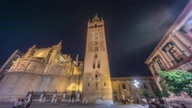 La Giralda ve Seville Katedrali geceleri aşırı hızlanarak altın ışıklarla parıldıyor. Tarihi çan kulesi, gotik detaylar ve aydınlatılmış sokaklar Sevilla, İspanya 'da büyülü bir atmosfer yaratıyor.