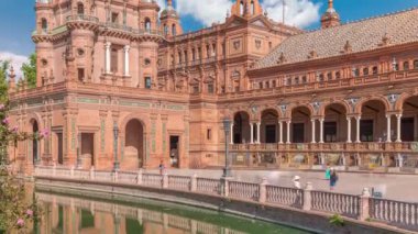 Seville Timelapse 'deki Plaza de Espana, Ibero-American Exposition için inşa edilen Maria Luisa Park' taki büyük bir mimari kompleks. Mavi bulutlu gökyüzünün altında kemerler, kanallar ve kırmızı duvarlar.