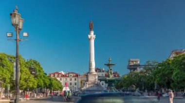 Gün batımında Rossio Meydanı 'nda dalgalı kaldırım taşları, çeşme ve IV. Pedro anıtı ile hızlandırılmış zaman aşımı. Arka planda trafik ve Santa Justa asansörü var. Lizbon, Portekiz