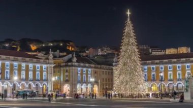 Lizbon 'daki ticaret meydanı, Noel' in aşırı hızıyla aydınlandı. Yükselen bir ağaç ve geceleri kutlayan kalabalıkla. Bir tepenin üzerindeki şenlikli atmosfer dekorasyonları ve tarihi mimarinin zamanı.