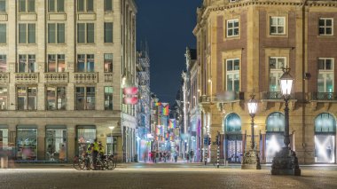 Amsterdam 'daki Baraj Meydanı' nda gece zaman dilimi, Hollanda. Şehrin tarihi merkezidir ve müzeler, dükkanlar ve oteller içerir. Aydınlatılmış Kalverstraat Caddesi