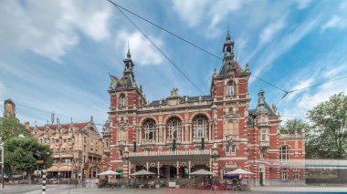 Uluslararası Amsterdam Tiyatrosu 'nun hiperlapası. Leidseplein' da yürüyen insanlar var. Tramvay dramatik bulutların altında tarihi binanın önünden geçiyor. Amsterdam, Hollanda