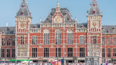 Amsterdam Merkez Tren İstasyonu 'nun zaman çizelgesi yaz günü mavi gökyüzünde bulutlarla kapanıyor. Amsterdam, Hollanda