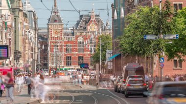 Damrak Caddesi, Dam Meydanı 'ndan Centraal İstasyonu' na giden, tramvaylı bir zaman diliminde. İnsanlar tramvay durağında beklerken trafik yolda ilerliyor. Amsterdam, Hollanda