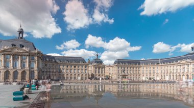 Place de la Bourse ve Miroir d 'eau hiperlapse Bordeaux, Fransa' da, tarihi mimariyi yansıtıyor. Turistler şehir simgesi ve çeşmenin tadını çıkarıyorlar. Trafik ve tramvay zamanı geçiyor..