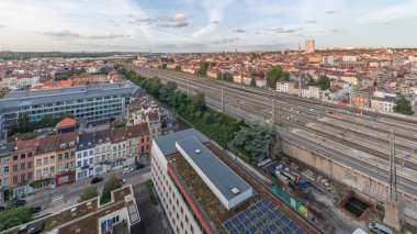 Brüksel Kuzey İstasyonu 'nun tren rayları, gelen ve giden trenlerle dolu. Schaerbeek akşam şehir manzarası kırmızı çatılar, sanayi bölgeleri ve bulutlu bir gökyüzü. Belçika