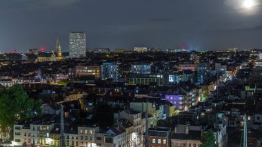 Brüksel üzerinde, Schaerbeek 'teki tren istasyonuna yakın gökdelende hava gecesi panoraması. Yerleşim yerleri, aydınlatılmış Saint-Servais Kilisesi Belçika 'nın başkentindeki kırmızı çatılarla çevrili.