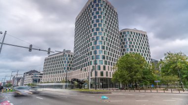 Timelapse of traffic and modern office buildings in the business district on Boulevard Baudouin, Brussels, Belgium. Contemporary towers near an intersection and park under a cloudy sky clipart