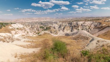 Red Valley and Rose Valley of Goreme of Nevsehir in Cappadocia aerial timelapse, Turkey. Love valley and fairy chimneys panoramic view with clouds on a blue sky clipart