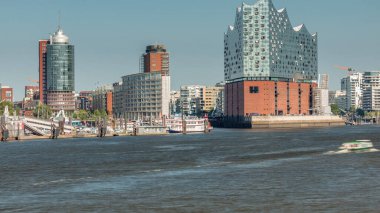 Hamburg 'un ikonik Elbphilharmonie konser salonunun ön planda gemileri ve tekneleri olan zaman çizelgesi. Arka planda Uberseebrucke ve Niederhafen, Hafencity rıhtımında. Almanya