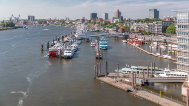 Almanya 'nın Hamburg kentinde Elbe nehir kenarının hava zaman çizelgesi. Rıhtımın yakınındaki Jan Fedder Gezinti Güvertesi, marina ve geçen gemilerle sahile manzara. Elbe Nehri kıyısındaki canlı şehir manzarası