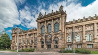 Hanover 'in Aşağı Saksonya Devlet Müzesi' nin trafik ve tarihi ön cephelerinin önünden geçen insanlar. Bulutlu gökyüzü, Almanya 'nın Niedersachsen zaman diliminde kültürel dönüm noktasını çerçeveledi