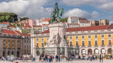 Praca do Comercio (Ticaret Meydanı). Kral 1. Jose 'nin heykeli. Kral sembolik olarak yoluna çıkan yılanları eziyor. Bulutlu bir gökyüzü ve arka planda renkli evler. Lizbon, Portekiz.