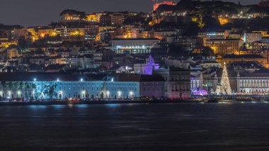 Lizbon Ticaret Meydanı 'nın Noel zamanı aydınlandı. Turistler, açılış ışık gösterisi sırasında parlayan ağacın ve dekorasyonların etrafında toplanıyorlar. Portekiz 'in başkentinde gece sahnesi