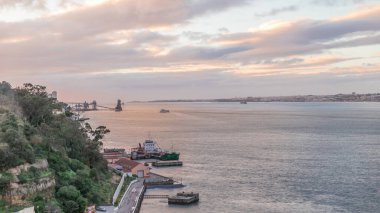 Aerial timelapse from a hill near Porto Brandao Ferry Station on the Tagus River in Lisbon. Dramatic sunset with colorful clouds, a ship floating on water and Terminal Portuario Trafaria in background clipart