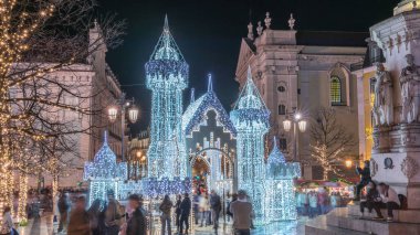 Lizbon, Portekiz 'deki Luis de Camoes meydanında aydınlatılmış şatoyla Noel süslemelerinin gece süreleri. İnsanlar festival ışıkları ve tarihi mimari etrafında yürüyorlar..