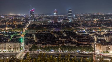 Geceleri Fourviere Hill 'den gökdelenlerle Lyon' un panoramik hava manzarası. Ufuk çizgisinde Rhone Nehri ve ikonik kent simgeleri yer alıyor. Evler çatılar ve caddelerde trafik